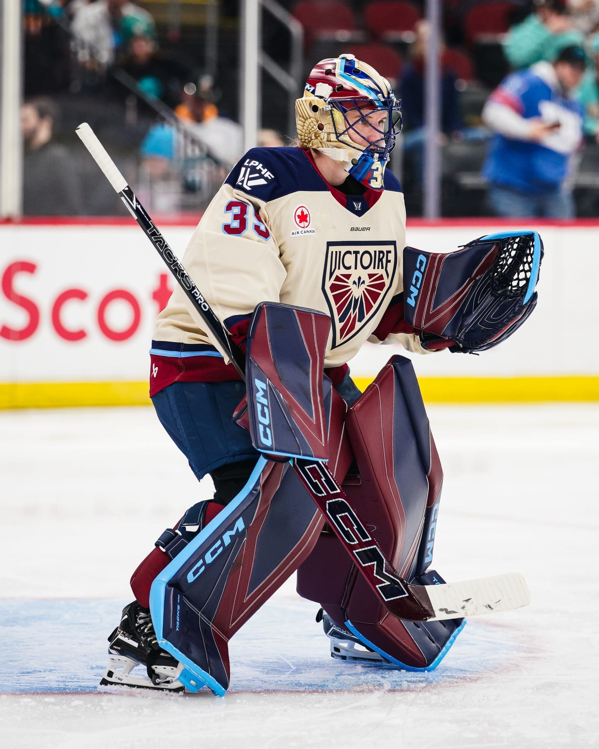 Montréal Victoire goaltender Ann-Renée Desbiens (35) stands in the crease wearing her cream and maroon away jersey and full CCM goalie gear, looking focused to her left during a stoppage in play.