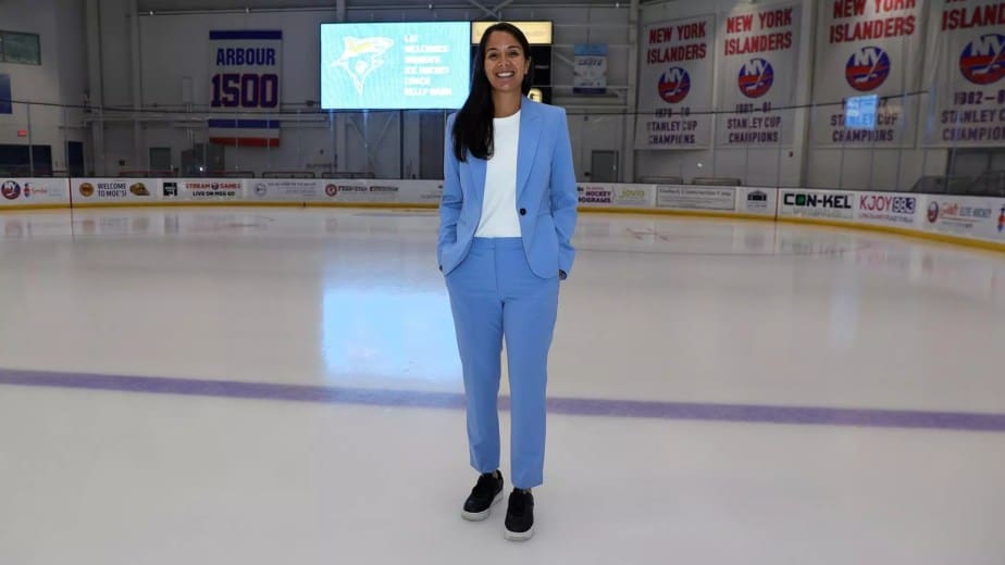 LIU women’s hockey head coach Kelly Nash stands on the ice between center ice and the blue line with the scoreboard behind her at Northwell Health Rink.