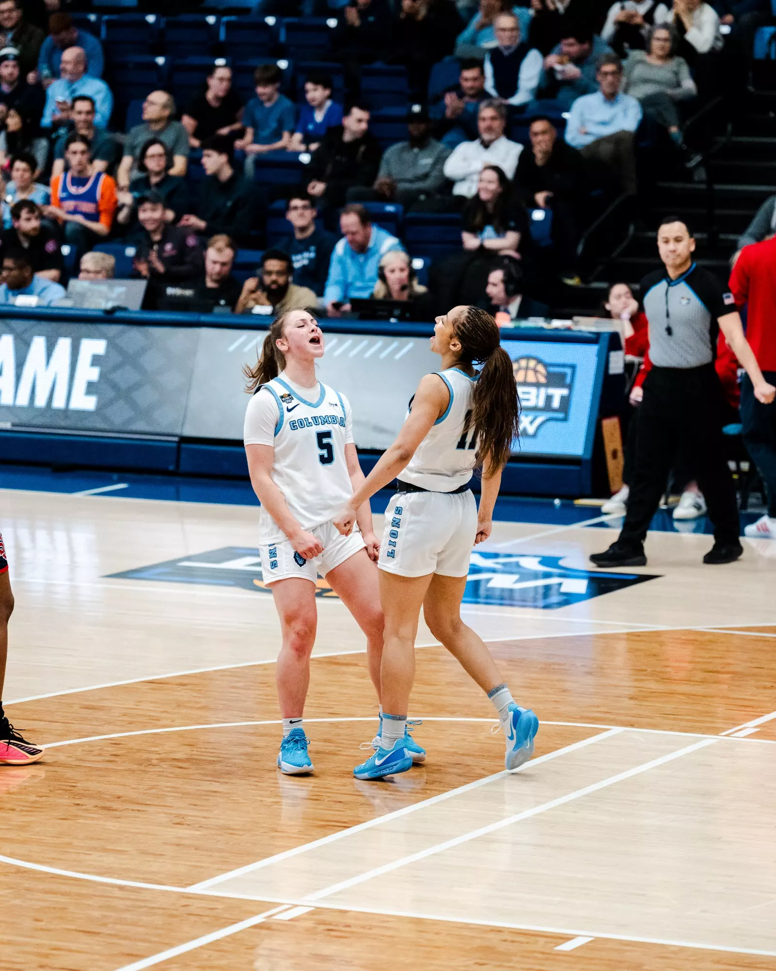 Two Columbia Lions players, Mia Broom and Nasi Simmons, celebrate on the court during a game.