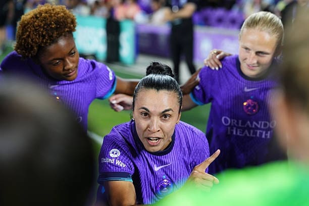 Orlando Pride captain Marta speaks to teammates in a pre‑match huddle at Inter&Co Stadium.