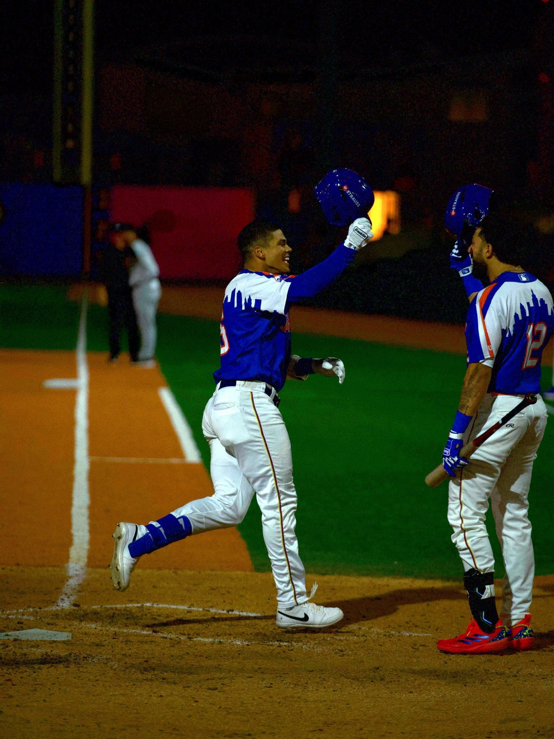 Brooklyn Cyclones infielder Mitch Voit celebrates after hitting a home run in the bottom of the eighth inning, raising his helmet as he approaches home plate to greet a teammate.