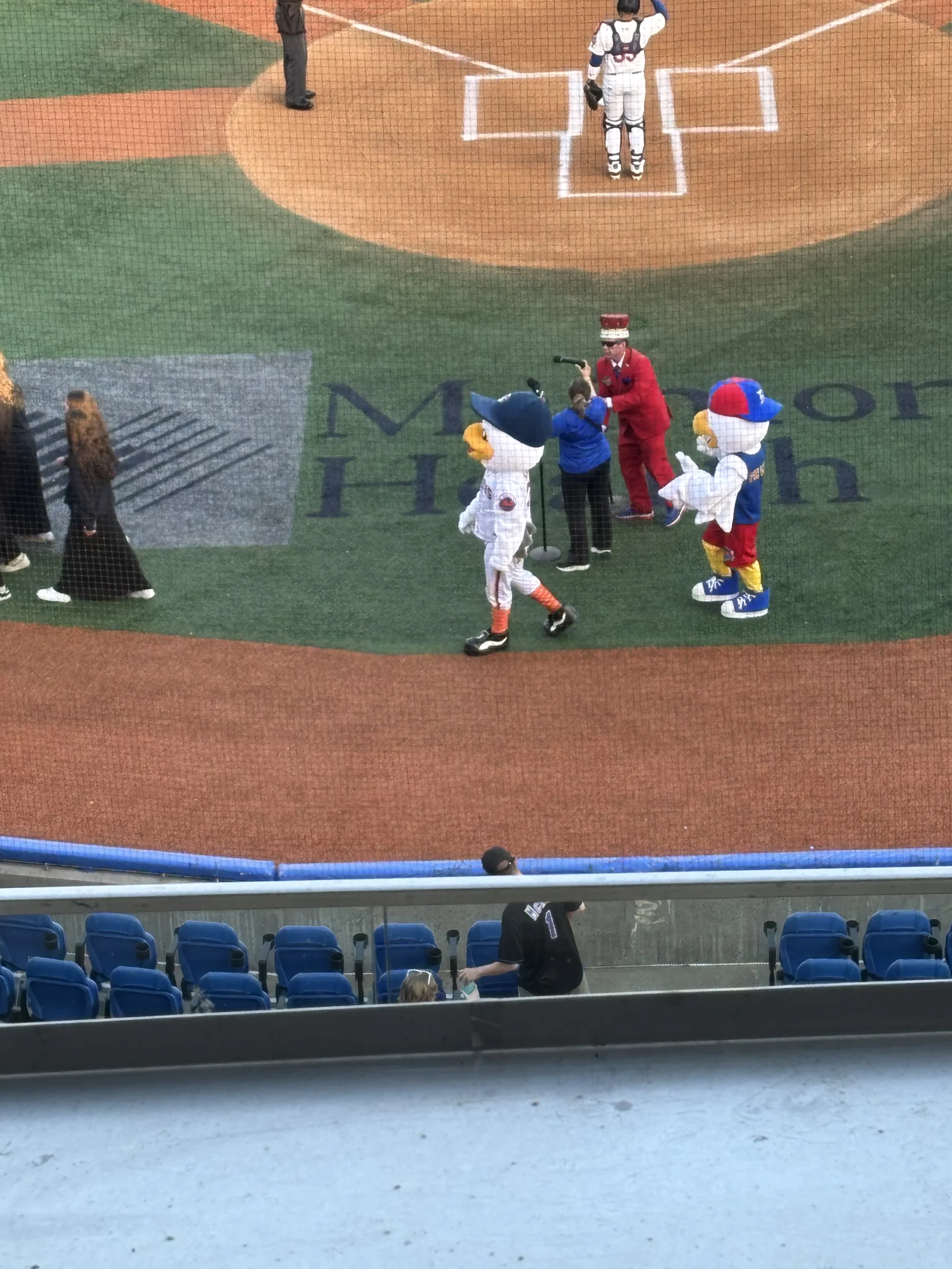 Two mascots and a Cyclones staff member interact with a child near home plate during pregame festivities at Maimonides Park.