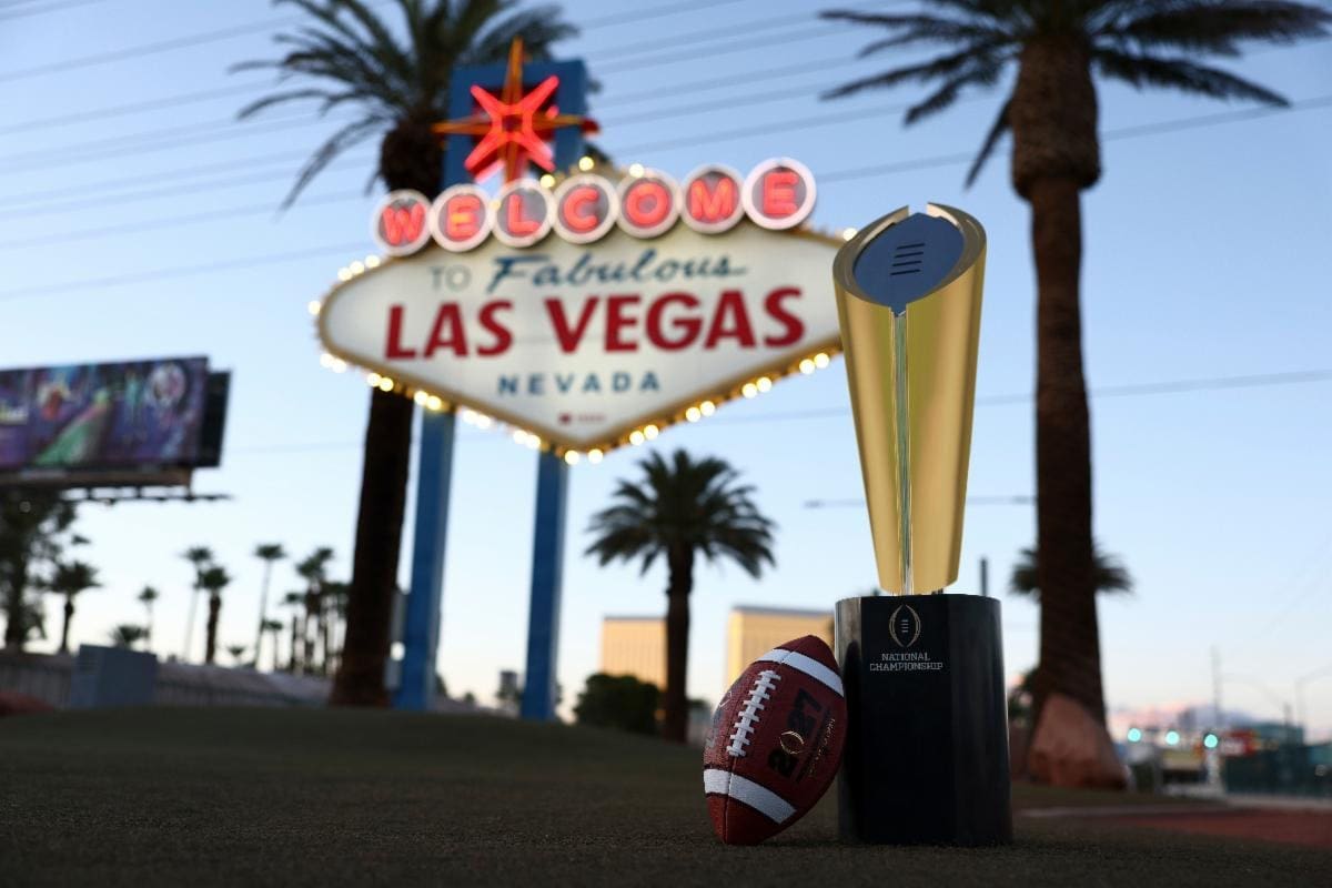 College Football Playoff National Championship trophy and 2027 football in front of the Welcome to Fabulous Las Vegas sign.