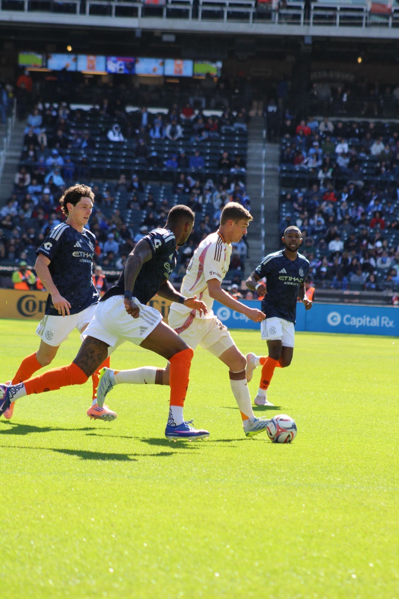 A D.C. United attacker dribbles through midfield while three NYCFC defenders close in during a match at Citi Field.